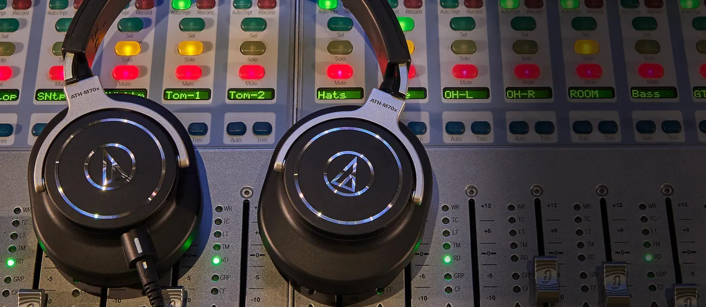 Deux casques ATH-M70x posés sur une console de mixage éclairée