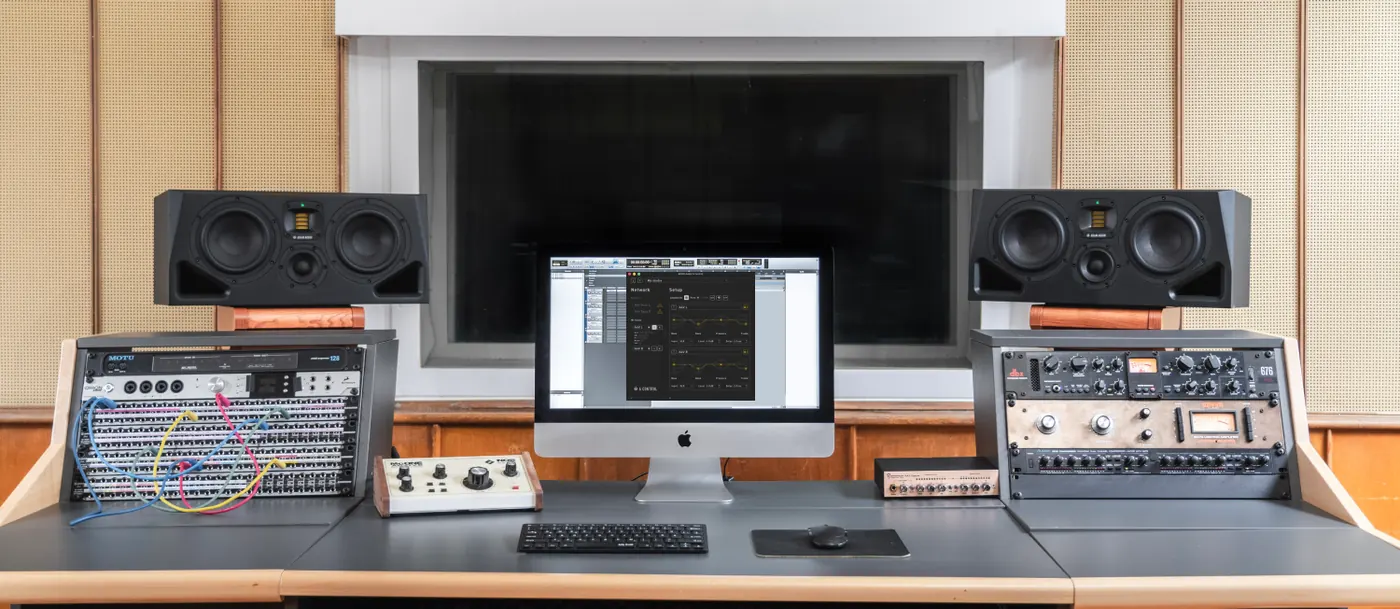 Régie d'enregistrement : deux moniteurs ADAM Audio A77H posés sur la console, de part et d'autre d'un grand écran