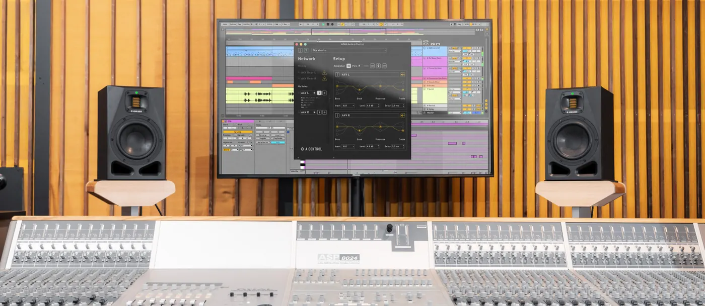 Studio d'enregistrement : deux moniteurs ADAM Audio A7V sur pieds, de part et d'autre d'un écran, derrière une grande console