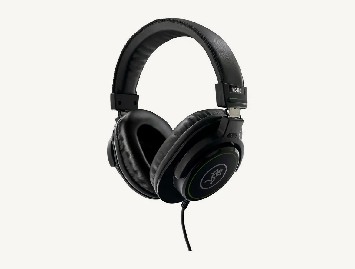 Casque de studio Mackie MC-100 vu de trois quarts, arceau rembourré noir, coque ornée du logo Mackie et câble à gauche