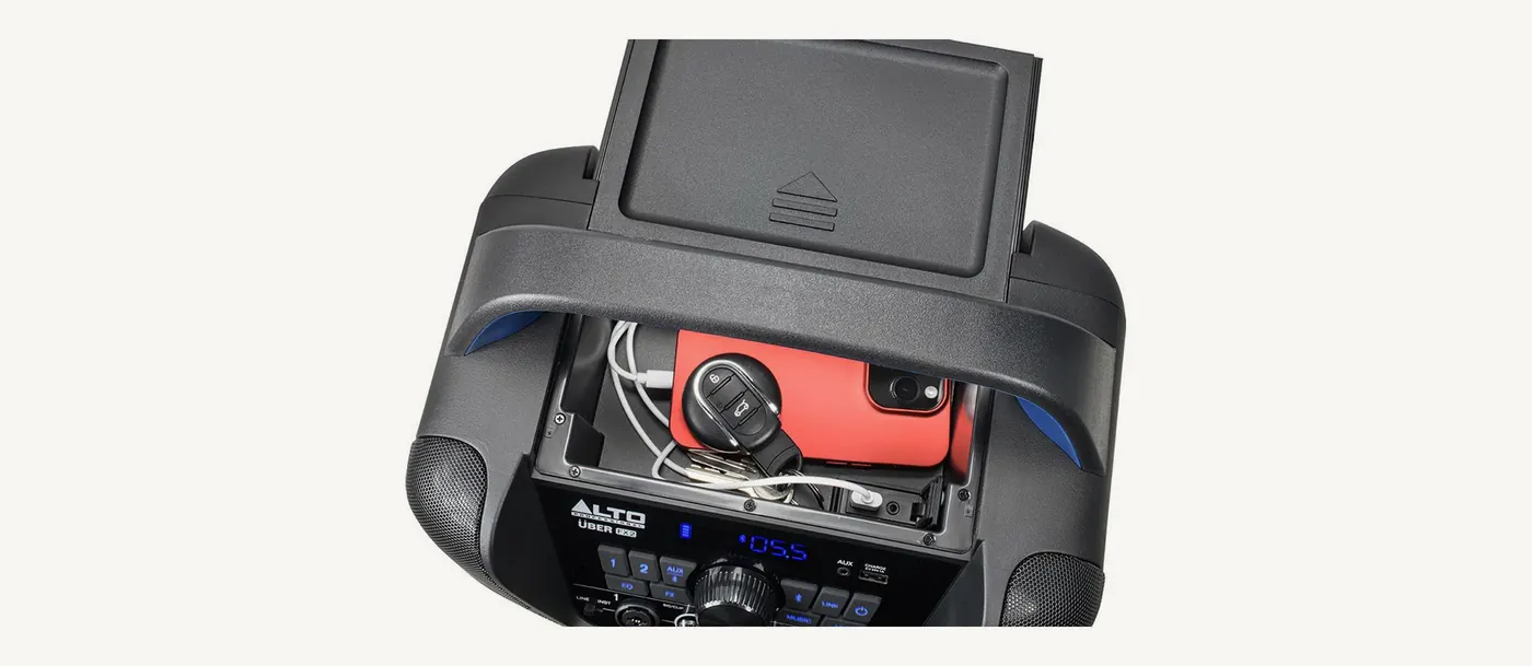 Compartiment du dessus de l'Uber FX2 ouvert, un téléphone et un câble de recharge rangés à l'intérieur