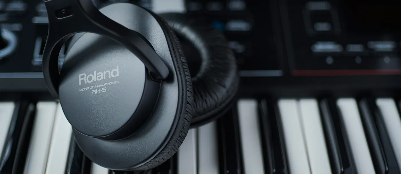 Casque Roland RH-5 posé sur le clavier d'un synthétiseur, coque argentée marquée Monitor Headphones RH-5