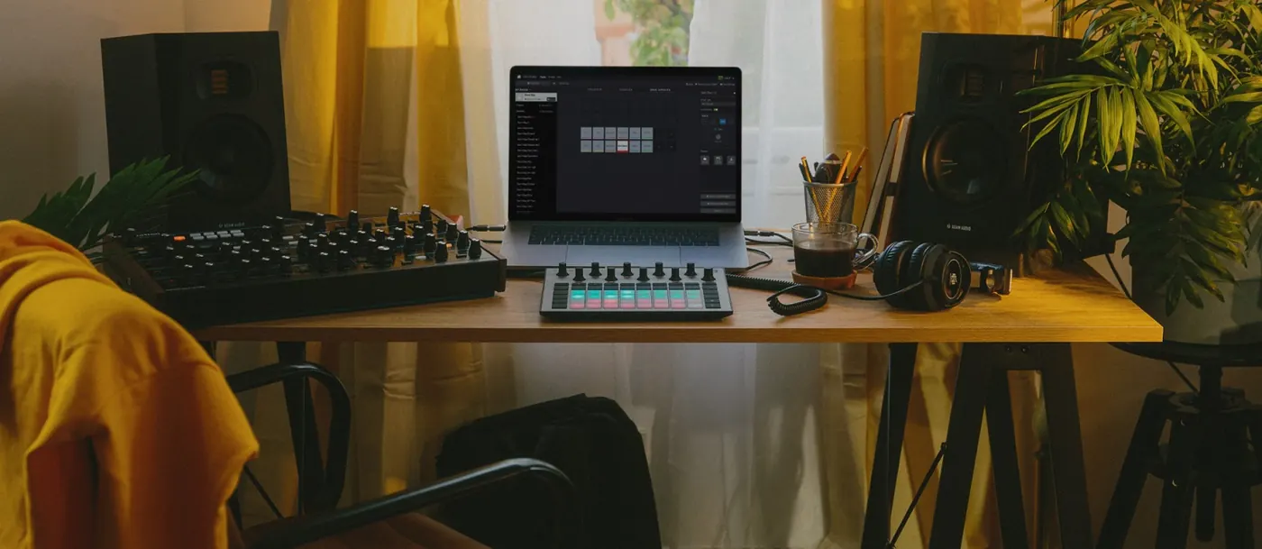 Poste de production : deux moniteurs ADAM Audio T5V sur un bureau, de part et d'autre d'un ordinateur portable et d'un contrôleur
