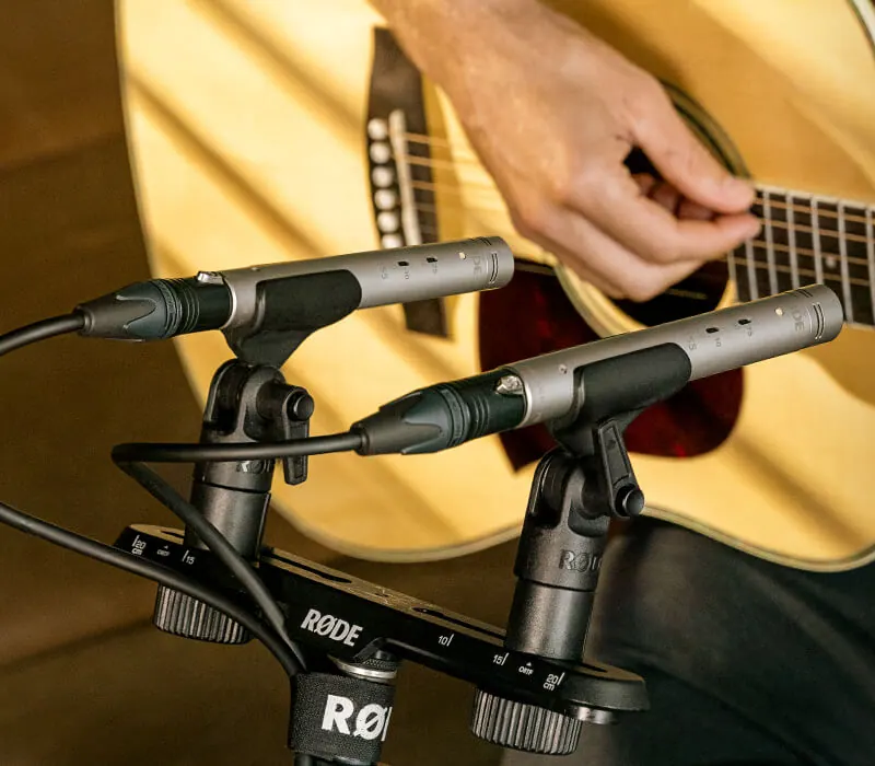Deux micros RODE NT55 en couple devant une guitare acoustique, montés sur une barre stéréo
