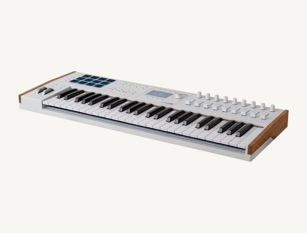 Clavier maître Arturia KeyLab 49 mk3 blanc vu de trois quarts, pads à gauche, écran et faders à droite, joues en bois