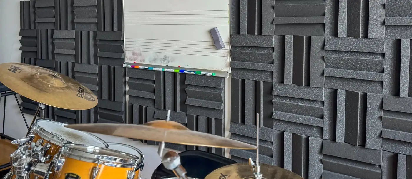 Panneaux Vicoustic MD55 posés en damier sur les murs d'une salle de répétition, batterie au premier plan