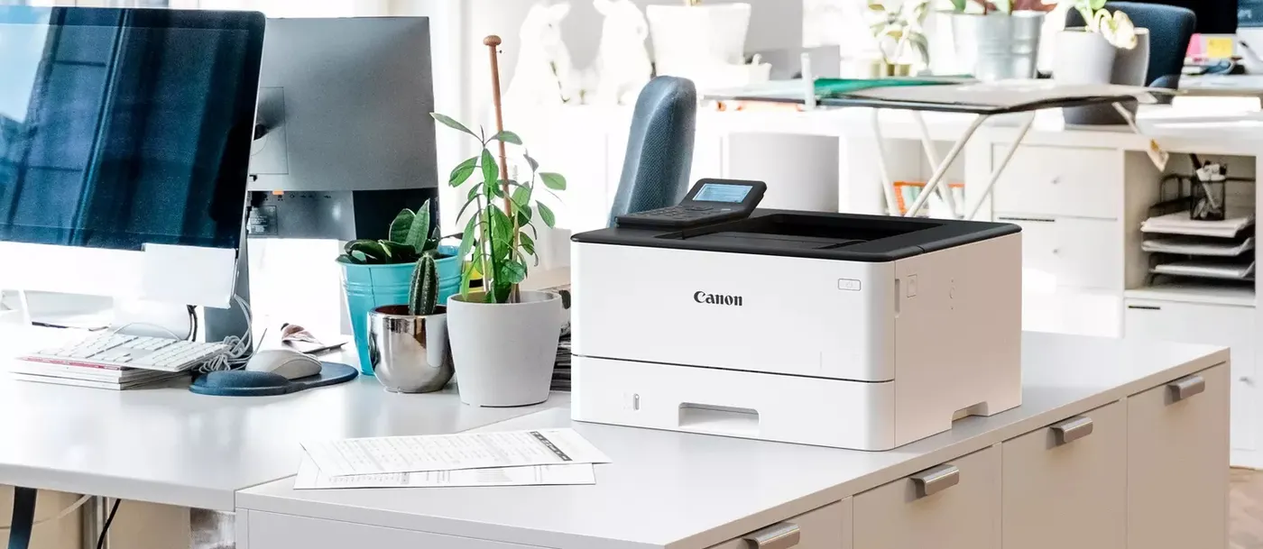 Imprimante laser Canon de la série LBP240 II posée sur un caisson dans un bureau lumineux