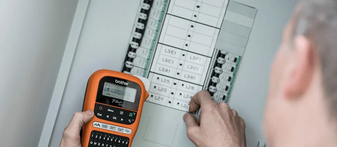 &Eacute;lectricien rep&eacute;rant les d&eacute;parts d&rsquo;un tableau &eacute;lectrique avec une &eacute;tiqueteuse Brother P-touch E110